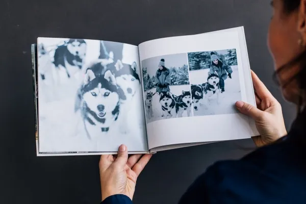 Открытая квадратная фотокнига, на страницах которой фотографии хаски и девушки