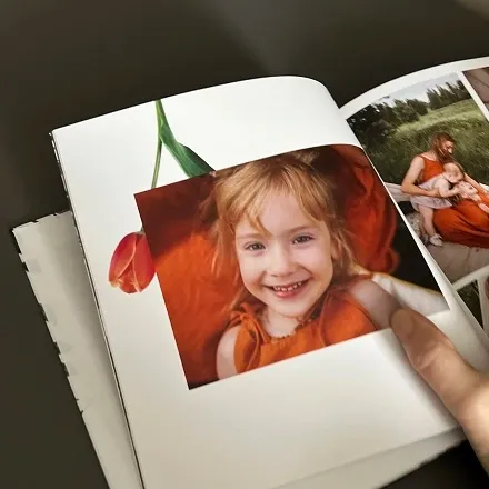 Открытая семейная фотокнига с фото улыбающейся девочки