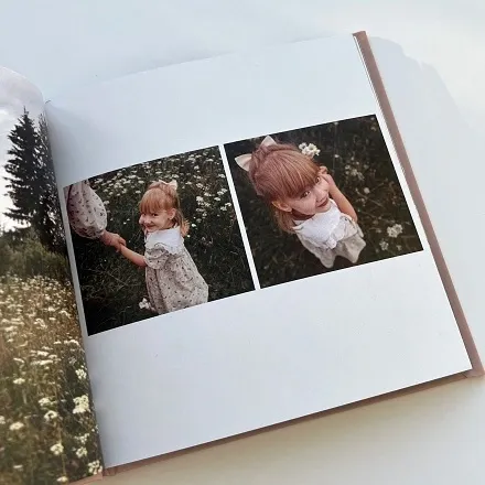 Открытая детская фотокнига с двумя фото девочки в поле среди ромашек